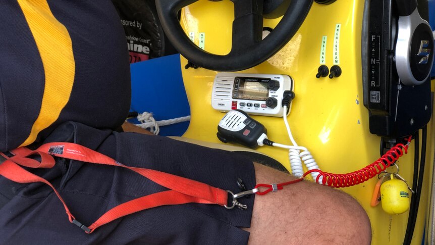 A red lanyard attached to a person and the ignition of a boat.