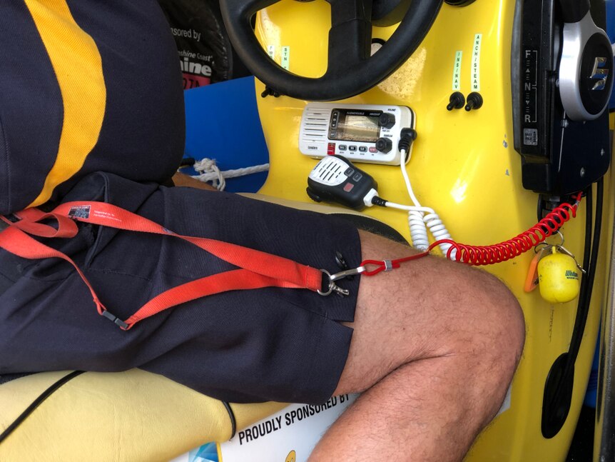 A red lanyard attached to a person and the ignition of a boat.