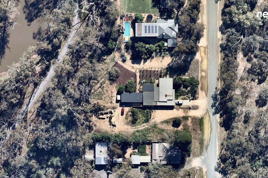 Three homes can be seen next to a river, with bushland opposite the houses