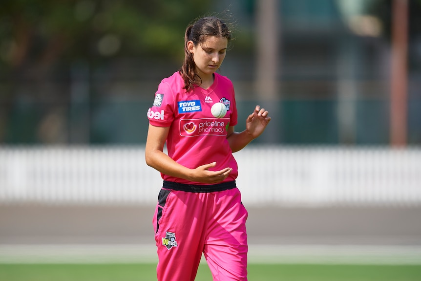 Sydney Sixers bowler Stella Campbell tosses a ball as she walks
