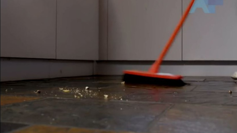 A broom on a floor beside debris