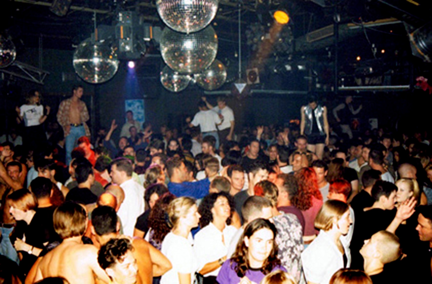 Pessoas dançando sob bolas de discoteca.