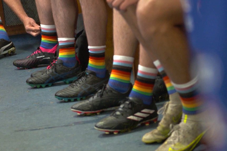 Men's legs with rainbow socks and football boots