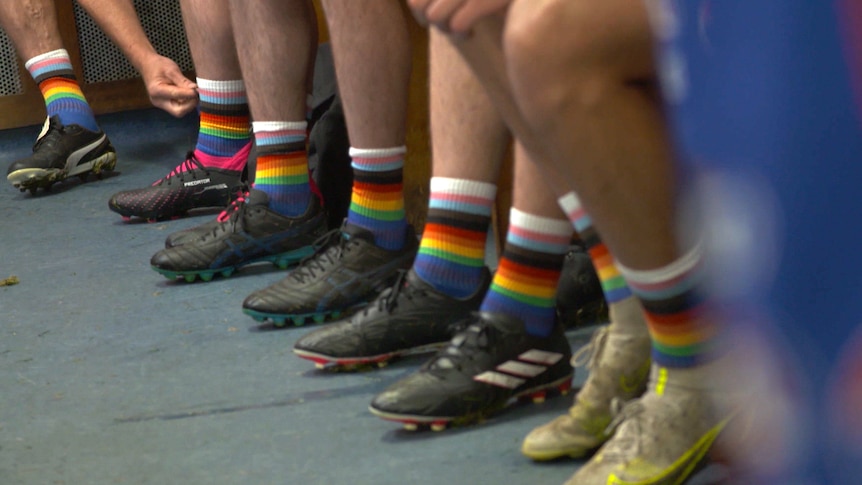 Men's legs with rainbow socks and football boots