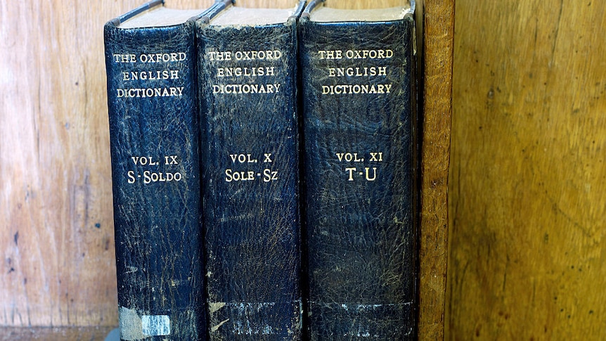 Three battered Oxford English dictionaries on a shelf