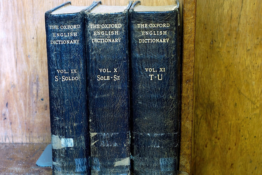 Blue spines of three battered Oxford English Dictionaries on a shelf.