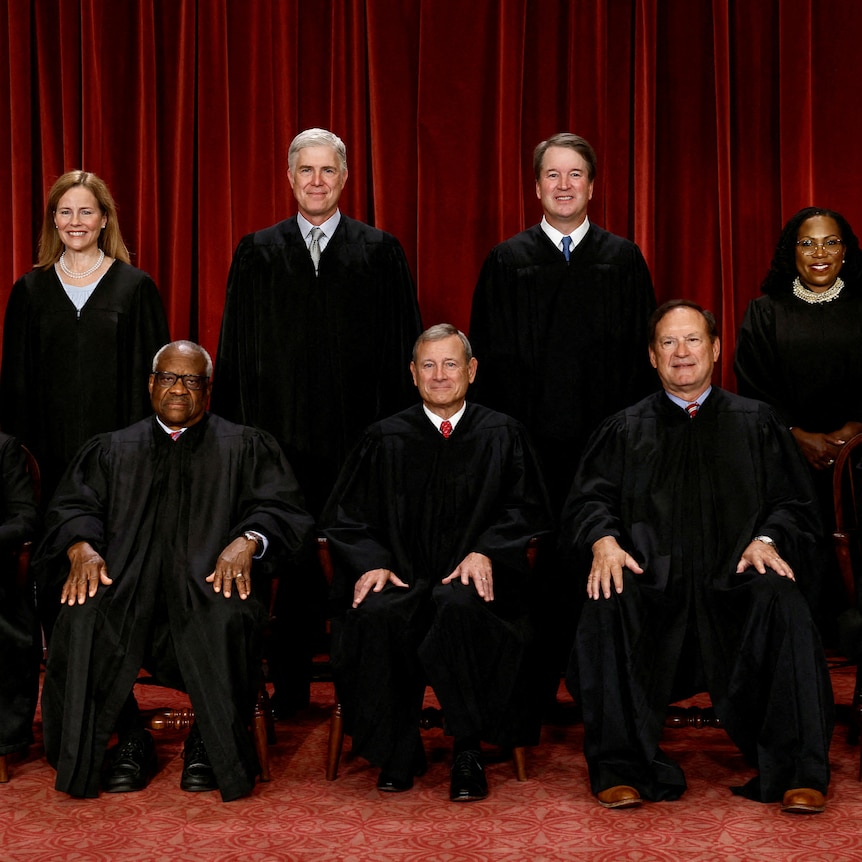 Supreme Court justices sitting and standing in black robes in official portrait.