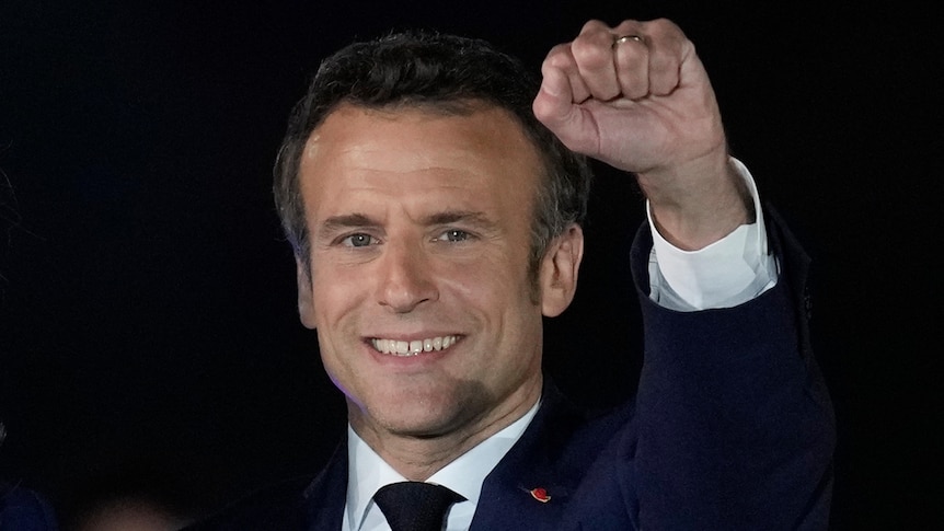 French President Emmanuel Macron smiles and holds up his fist while celebrating