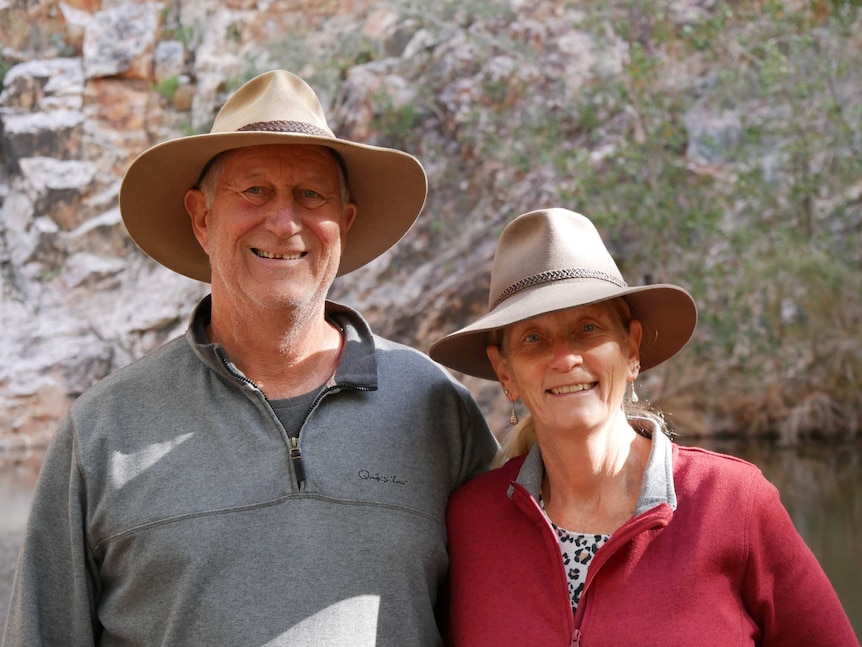 An older couple in bush hats smile for the camera