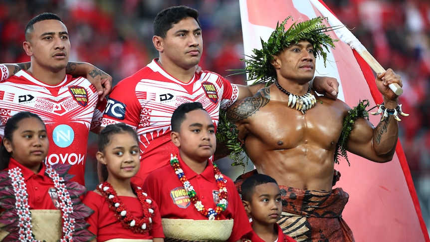 A group of Tongan men link arms for the national anthem 