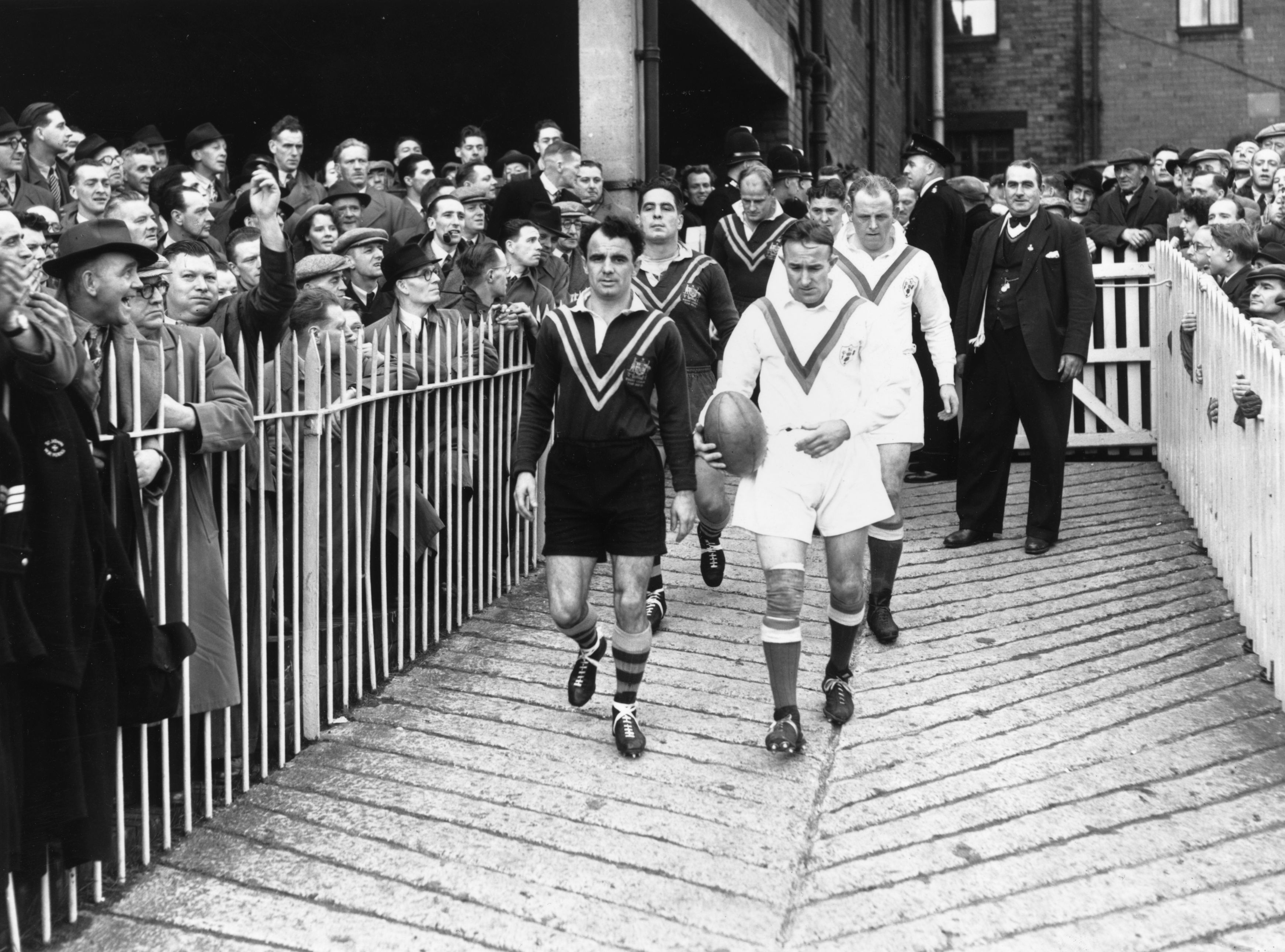 Two men lead rugby league teams on to the field 