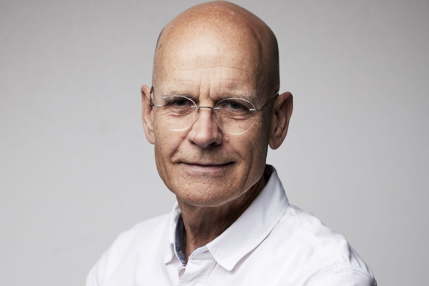 head and shoulders shot of man wearing glasses against a white background. 