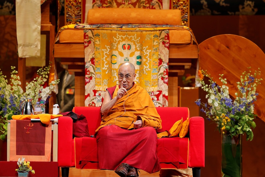 一名僧人坐在会有唐卡的寺庙内讲话