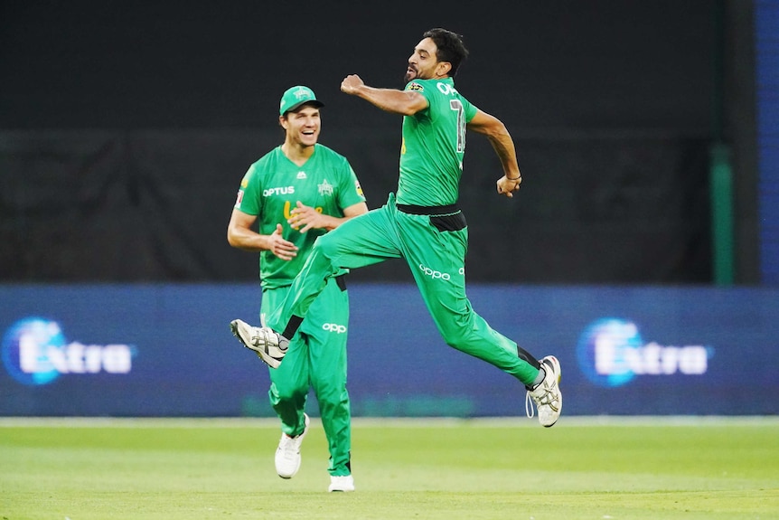A bowler is mid-leap with his legs outstretched and his fists pumping in celebration of a hat-trick.