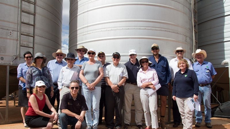 A group of people stand in front of a grain silo