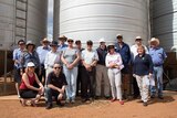 A group of people stand in front of a grain silo