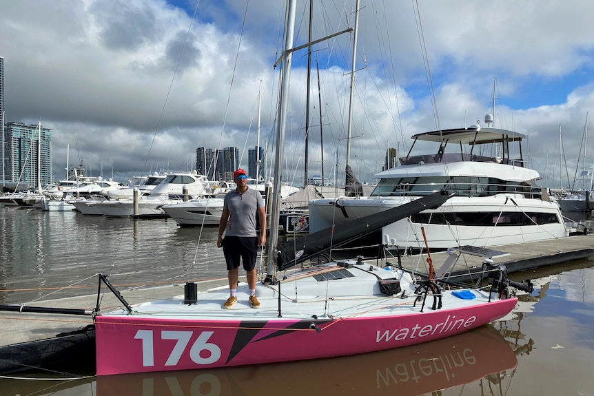 Homme debout sur le pont d'un yacht de 21 pieds pinte.