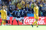 Jackson Irvine looks disappointed as the French team celebrate together in the background