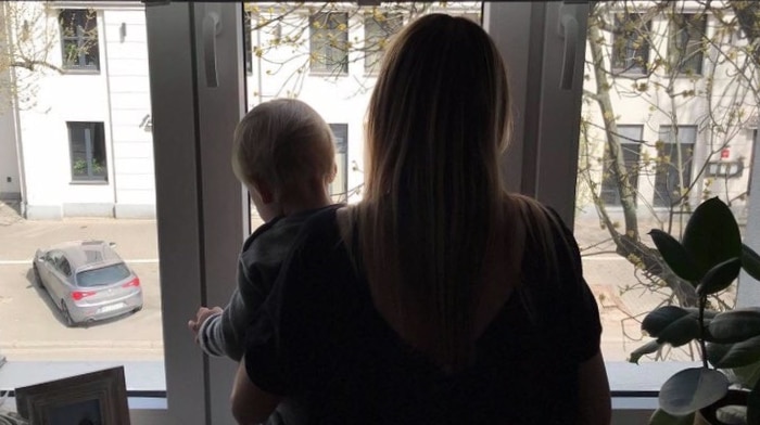 A woman holding small child looks out her window