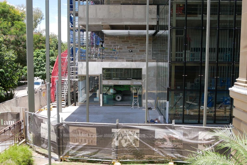 A tall building under construction on a riverbank.