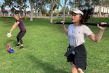 Three women take part in an exercise class in a park.