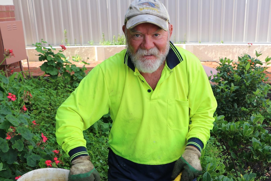 Bearded man in white cap and fluoro green top sitting in garden