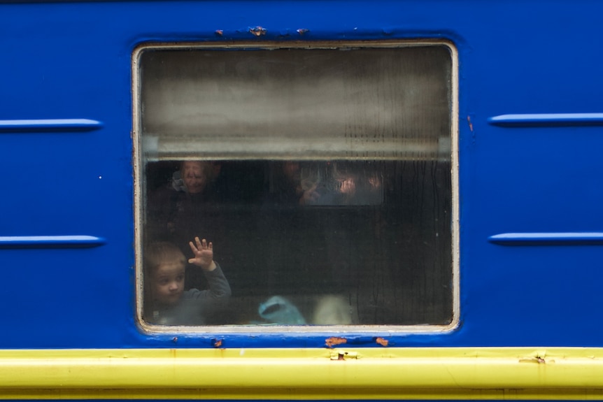 A little boy watches as his blue and yellow train leaves Kyiv station.