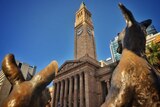 Close-up of a kangaroo statues outside Brisbane City Hall looking up at clock tower towards the sky.