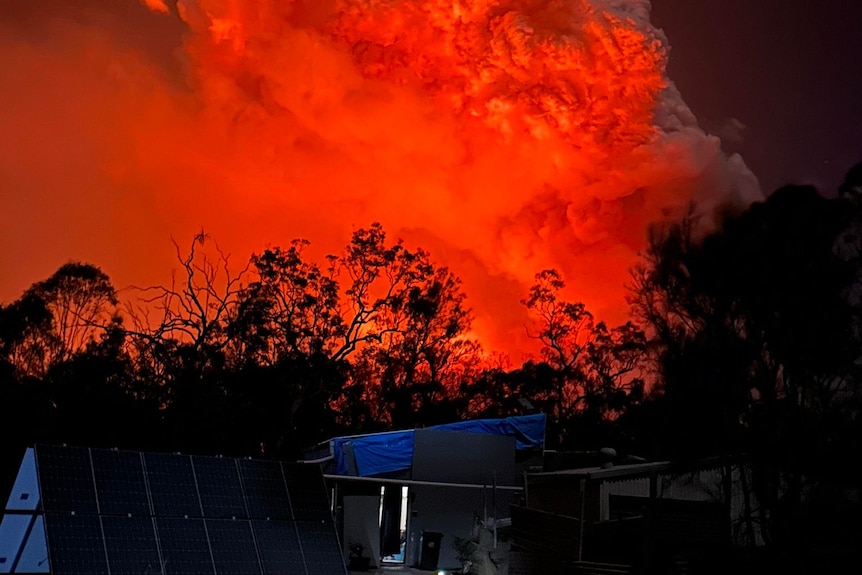 a cloud of red smoke as fire burns through the night