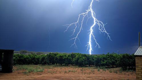 Large lightening strikes light up the night sky over a field.