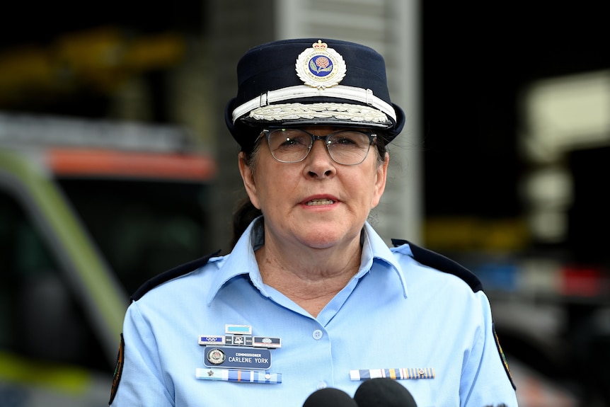 a woman wearing glasses wearing a police cap and talking