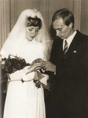 A black and white photo of young Vladimir Putin standing with a young woman in a bridal gown