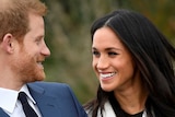 Meghan (left) smiles at Prince Harry