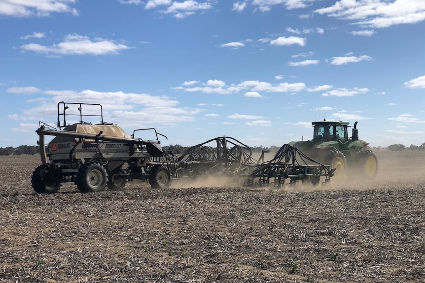 Machinery sowing seeds in an empty paddock.