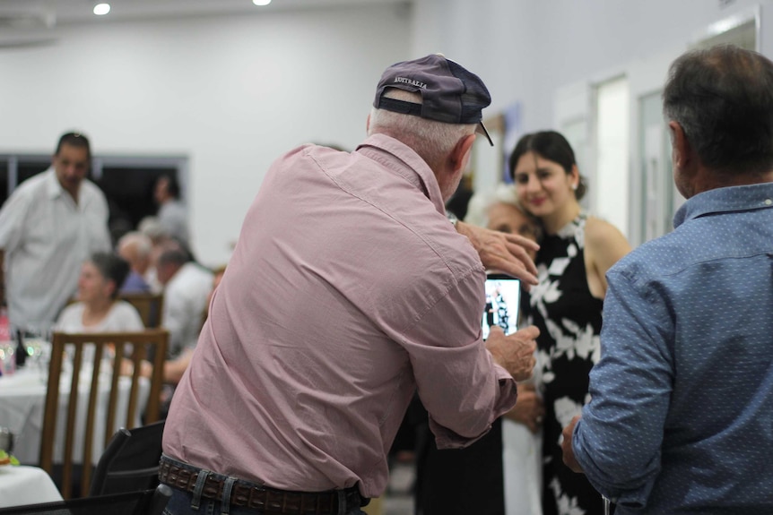 People at a cocktail party take photos of each other.