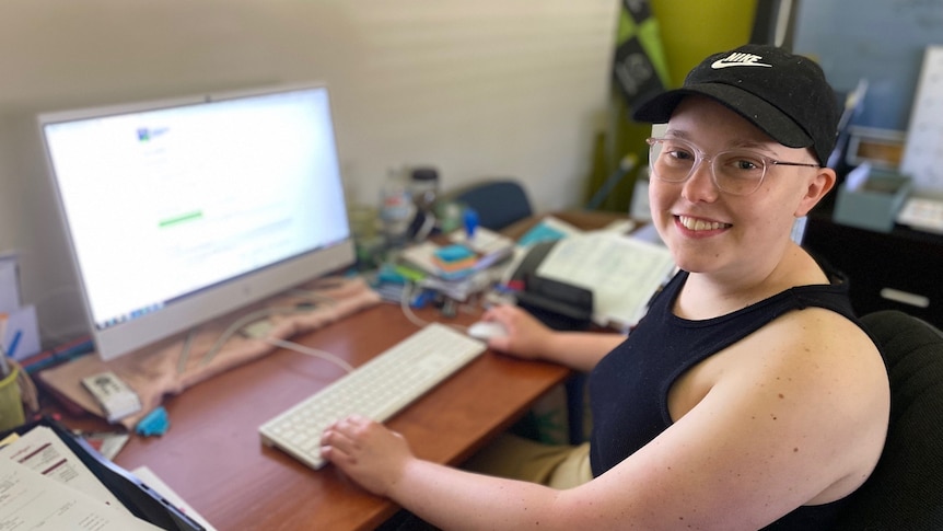 young female student wearing a black hat sitting at a computer