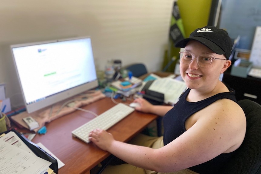 young female student wearing a black hat sitting at a computer