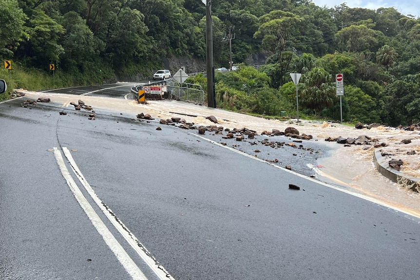 water, rocks over mountainside road