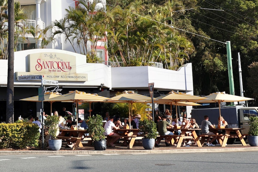 People sitting at picnic tables outside of a bar