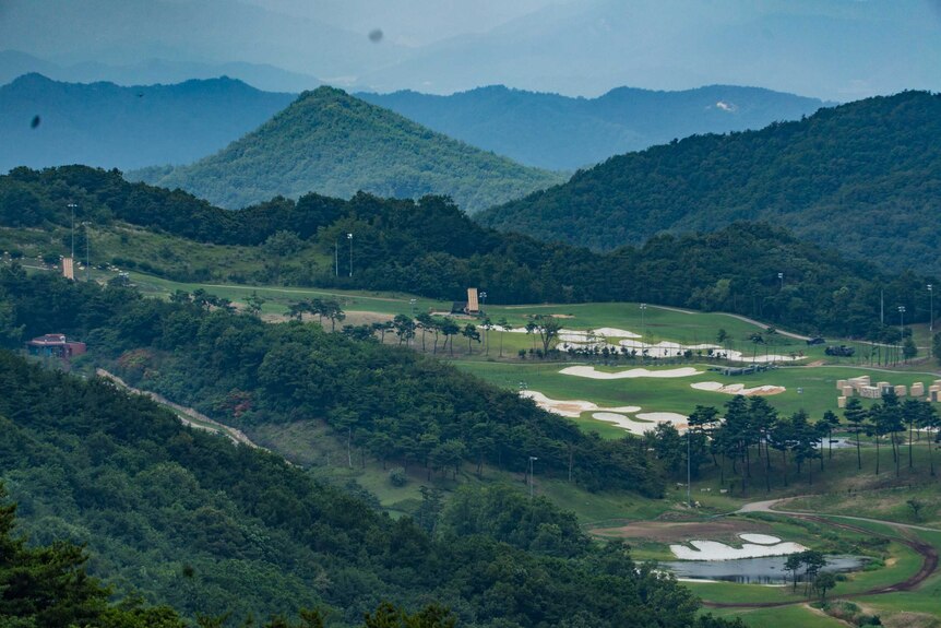 The THAAD missile defence system stands in the distance on a gold course in a green valley.