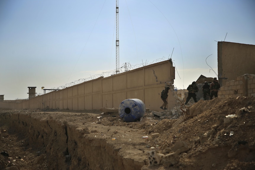 Soldiers looking through a hole in a fence 