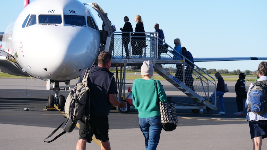 people walking on tarmac to Qantas plane