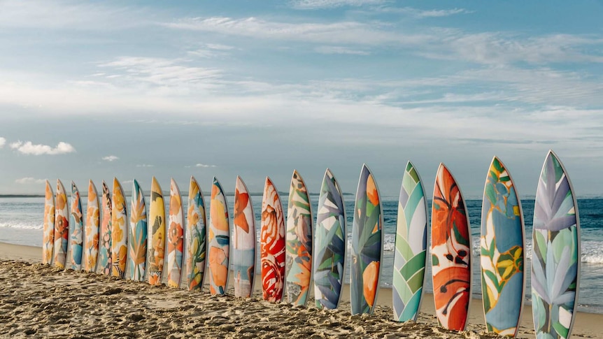 Brightly coloured surfboards placed on sand along One Mile beach, Forster.