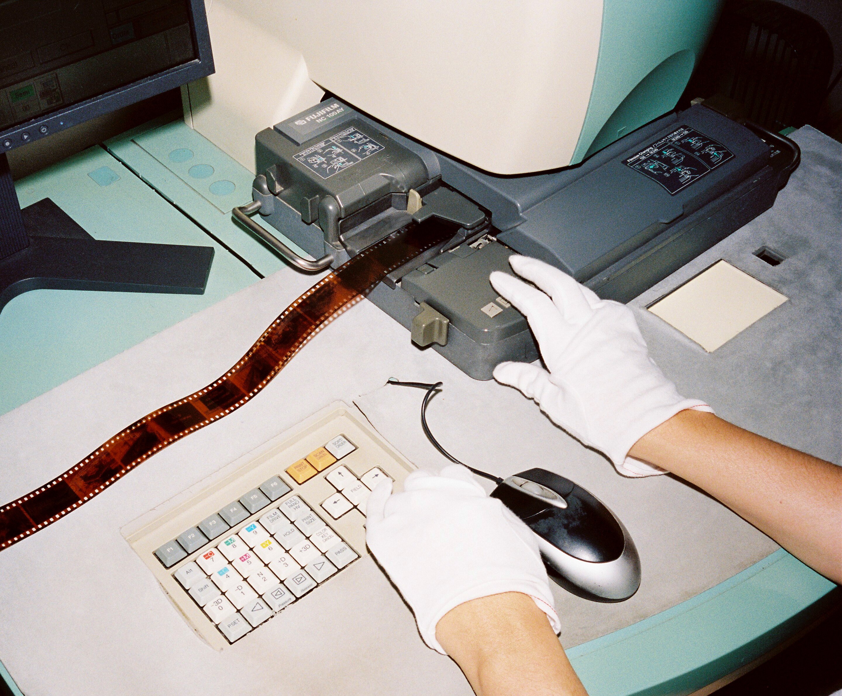  A film photo of a gloved hand printing brown negatives on film
