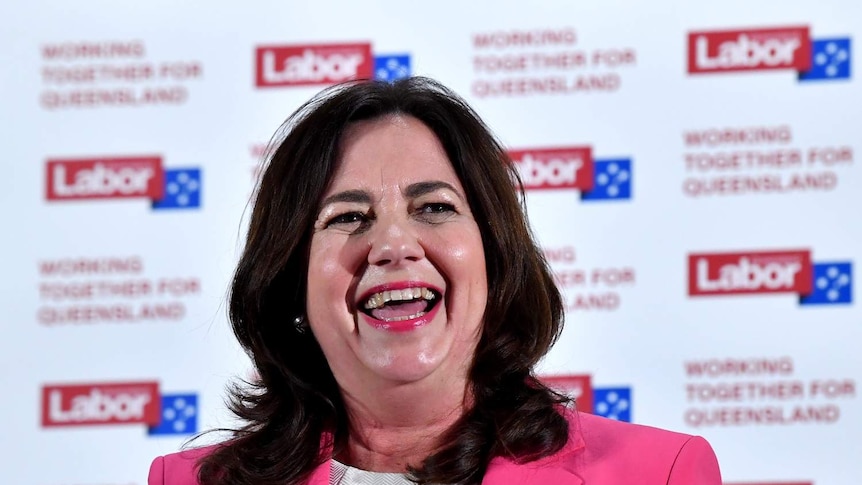 Queensland Premier Annastacia Palaszczuk smiling in front of Labor signage.