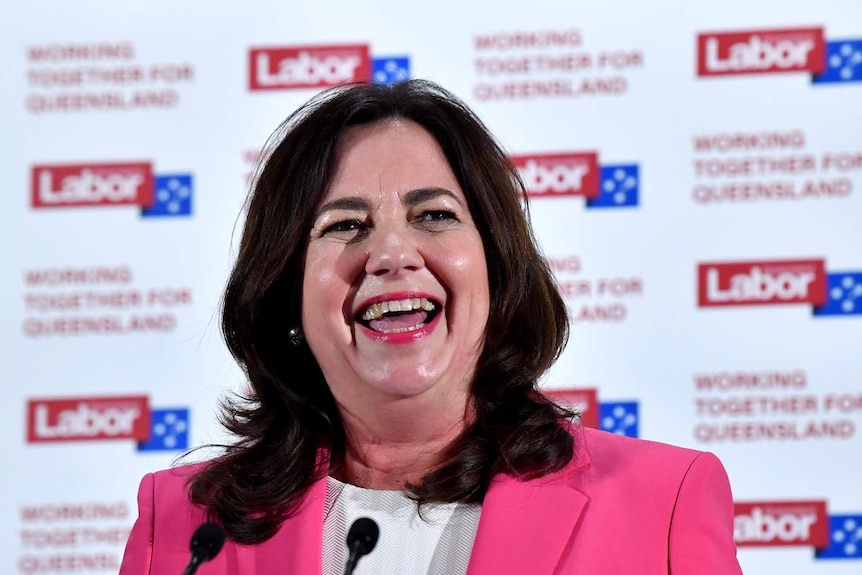 Queensland Premier Annastacia Palaszczuk smiling in front of Labor signage.