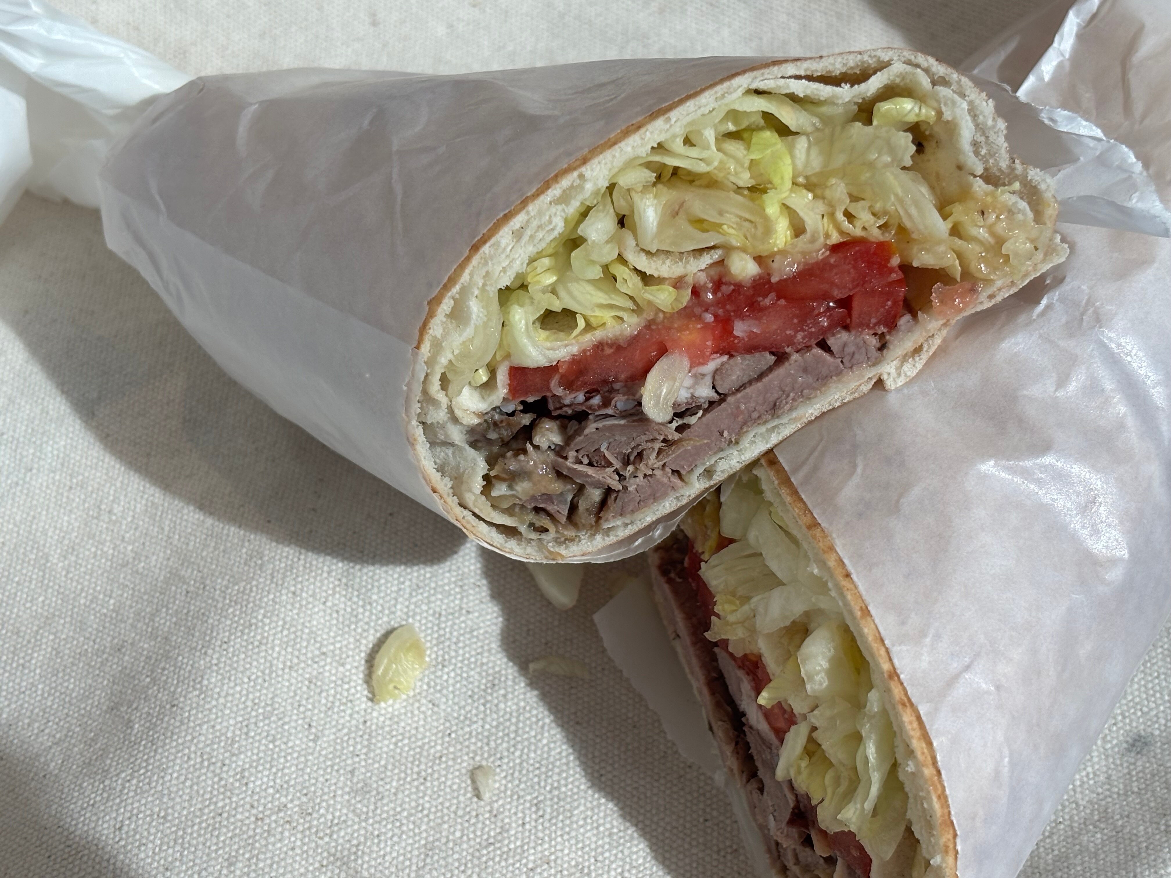 Slow cooked lamb shoulder wrapped in pita bread with lettuce, tomato, baba ganoush, and onion. 