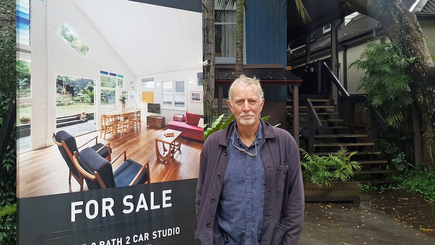 Peter Giutronich stands next to a for sale sign outside his house.