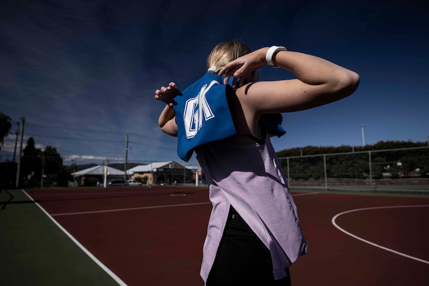 Girl putting on netball singlet