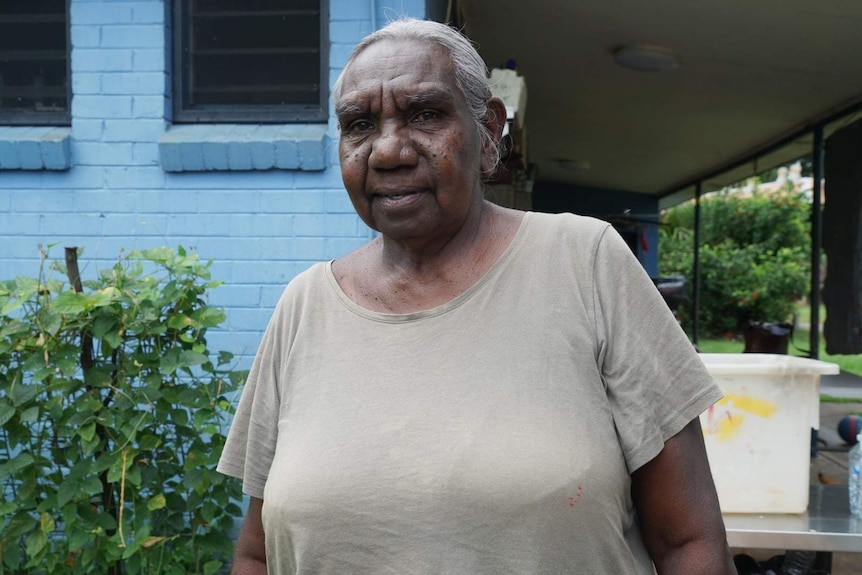 An older Indigenous woman stands in the backyard of her home in Nauiyu community.